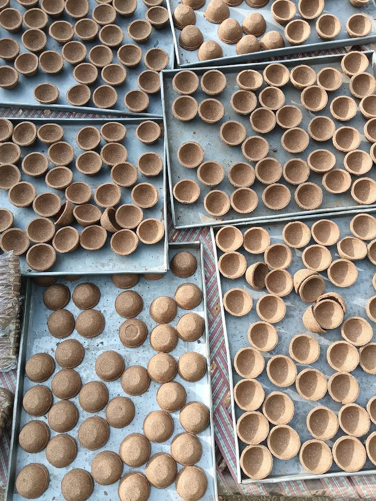 Cow-dung diyas drying on trays at the gaushala